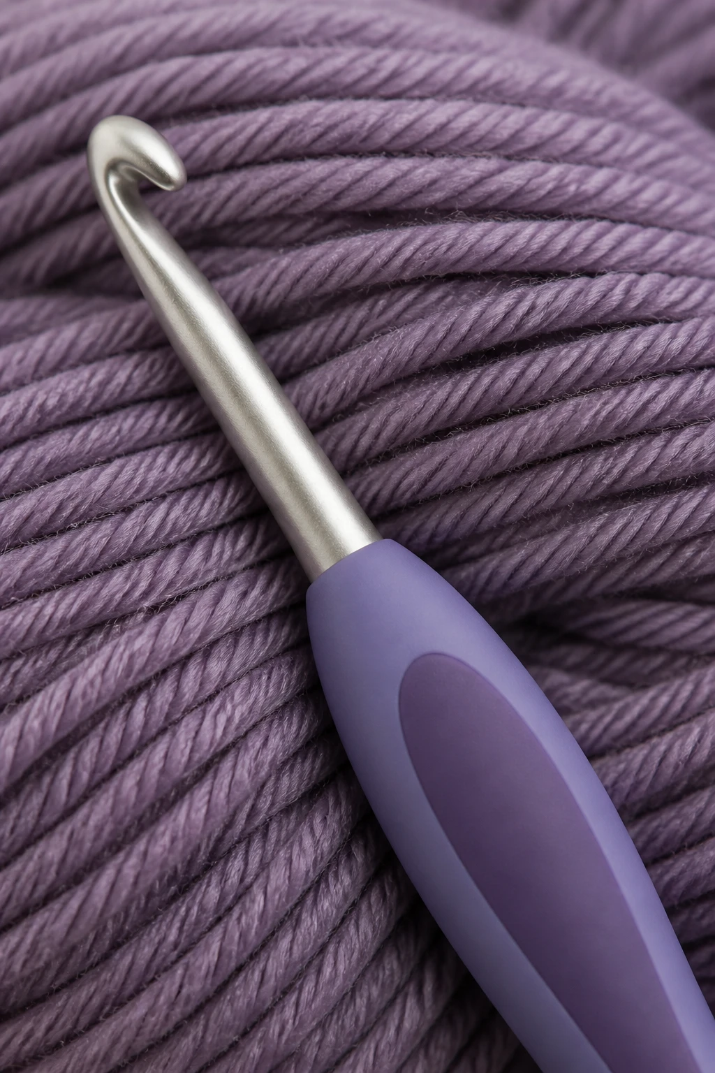 Closeup of G/6 crochet hook with ergonomic grip in front of smooth worsted yarn
