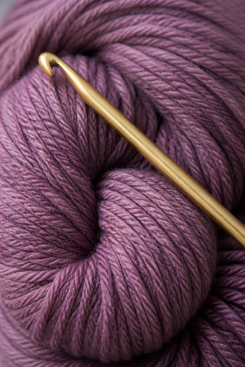 Macro shot of a single skein of yarn and a lone crochet hook resting atop it