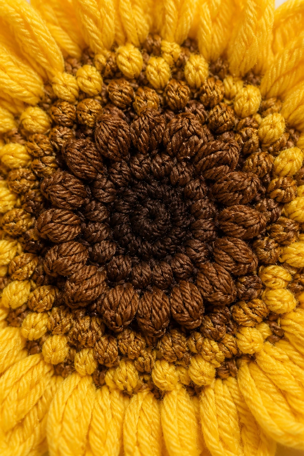 Closeup of a crochet sunflower center with layered brown/yellow textures