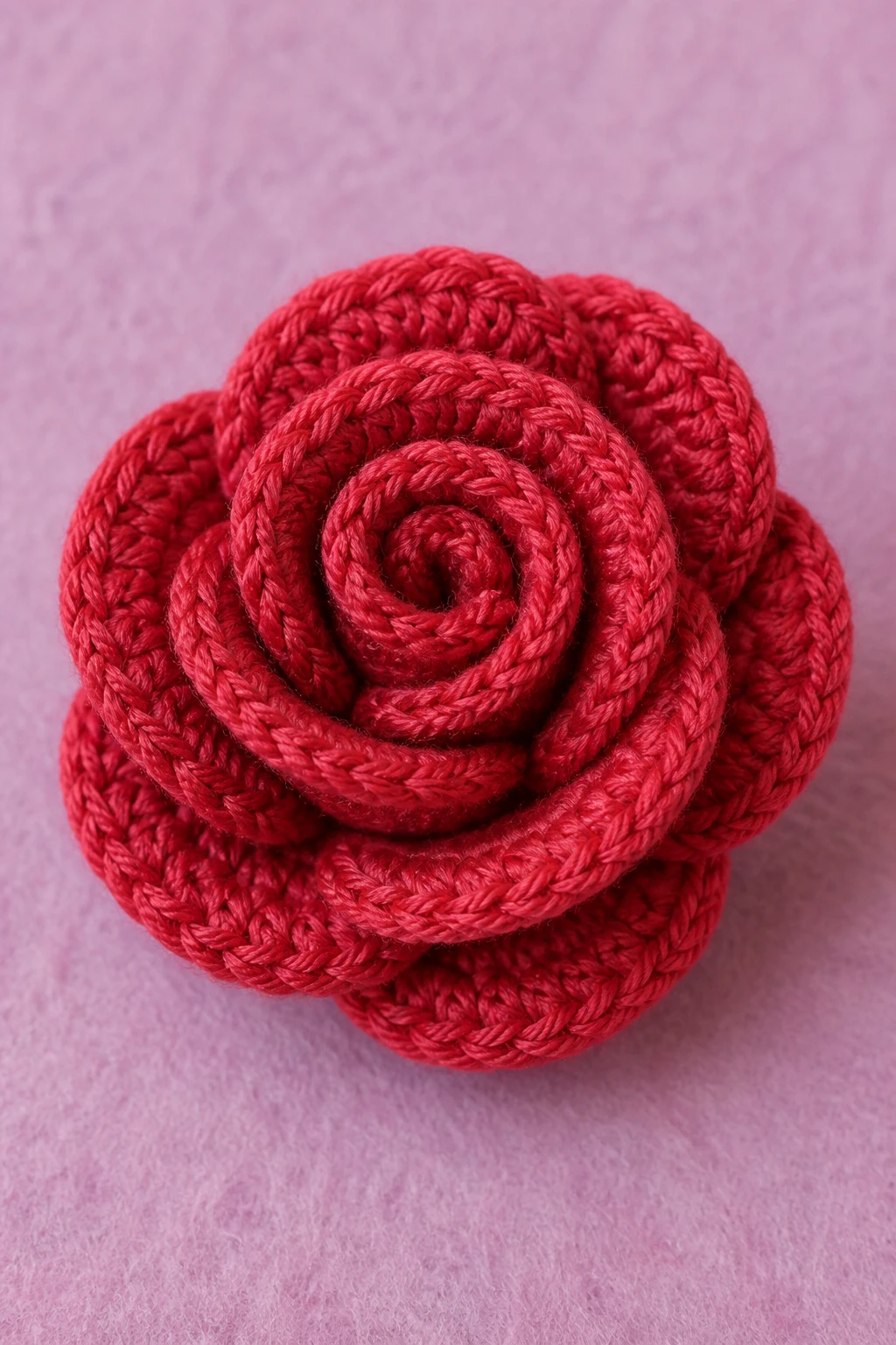 Closeup of a single crochet rose on pastel felt background