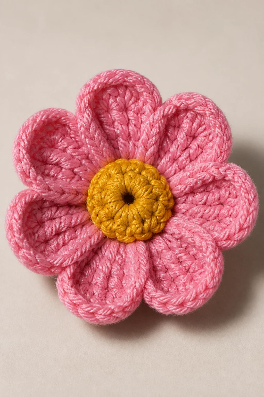 Closeup of a single crocheted bloom avec defined center, soft shadow, neutral backdrop