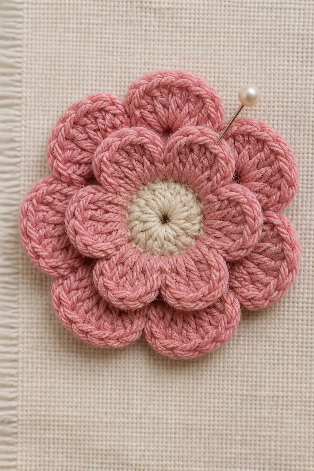 Closeup of a flat crochet blossom pinned to textile swatch