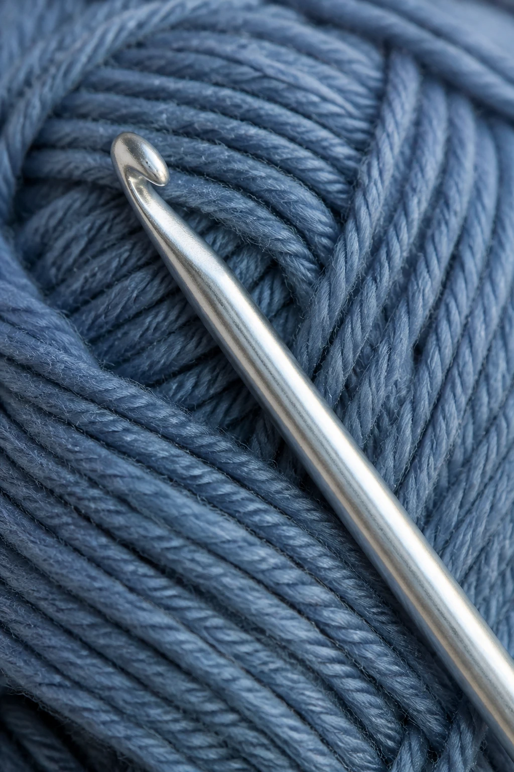 Closeup of a single aluminum crochet hook on yarn skein