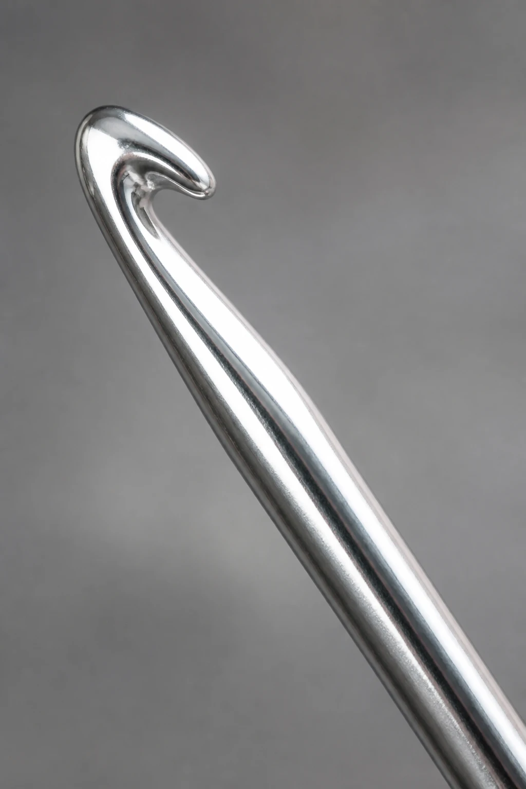 Closeup of a single metallic aluminum crochet hook gleaming under light