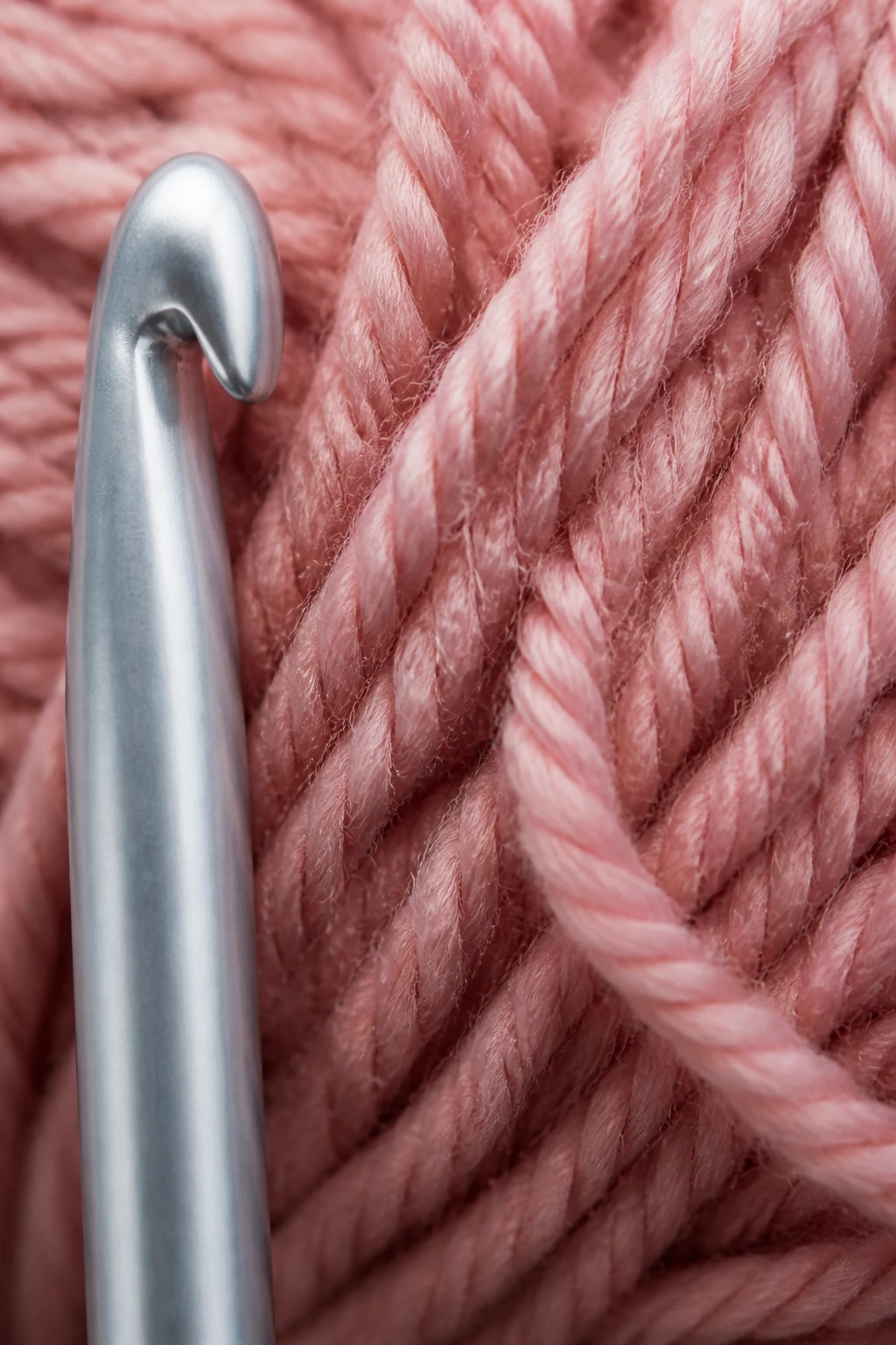 Macro shot of one aluminum crochet hook beside yarn texture