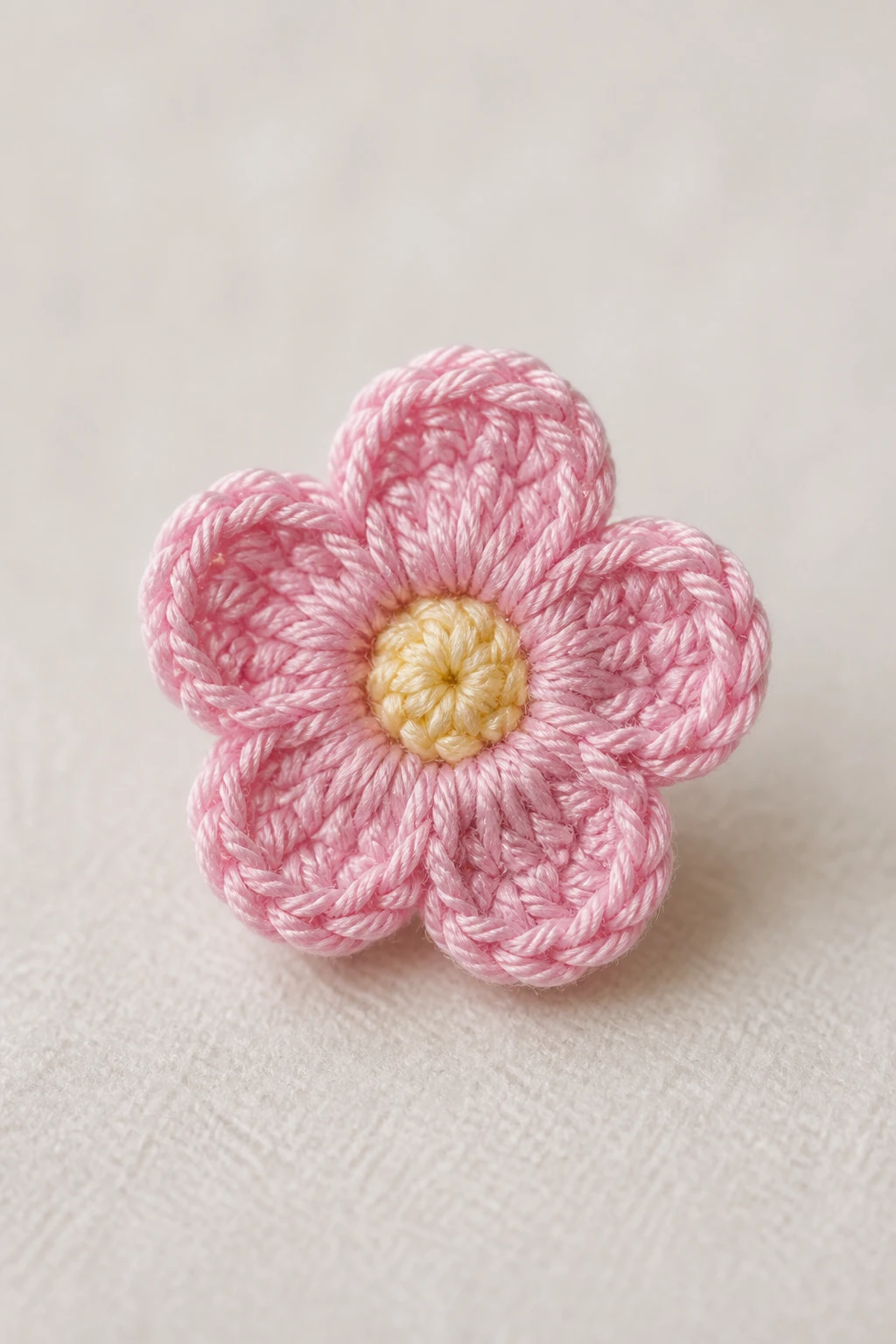 Solo tiny crochet bloom with crisp stitches against soft neutral backdrop