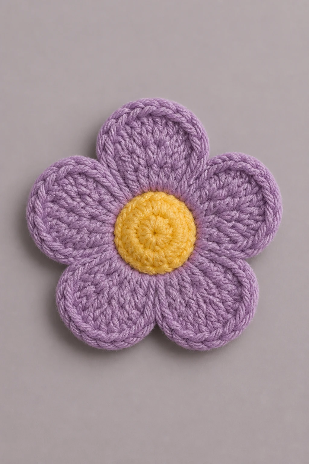 Isolated crochet flower, neatly joined petals, on smooth matte surface