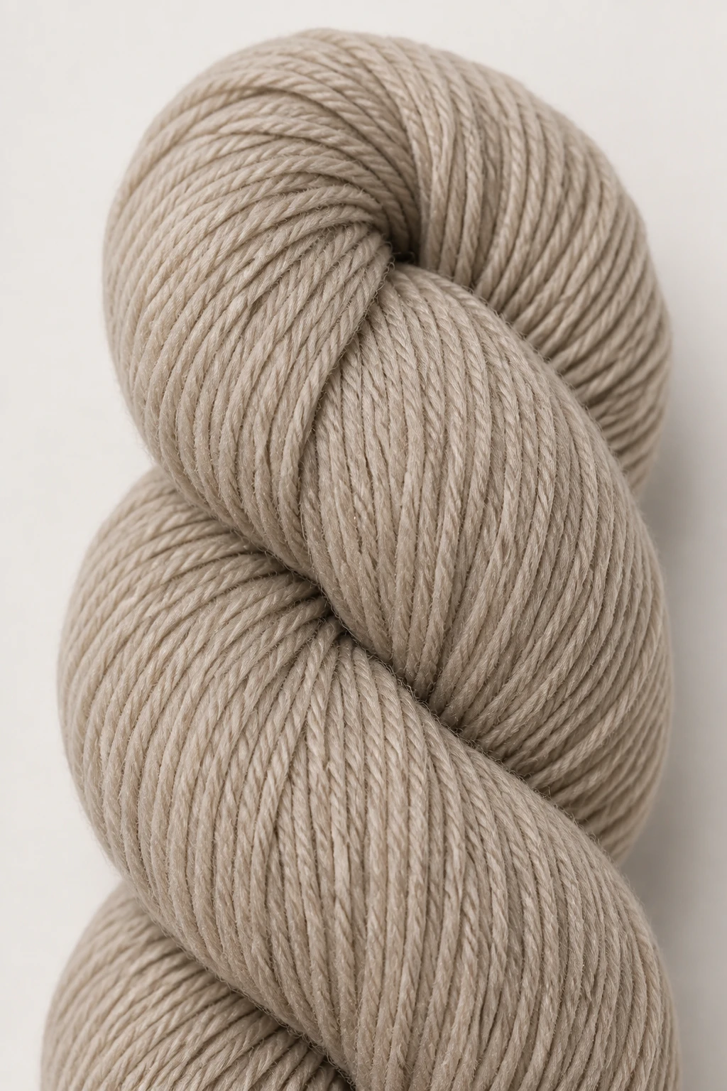 Close-up of a single skein of neutral worsted yarn on a plain backdrop