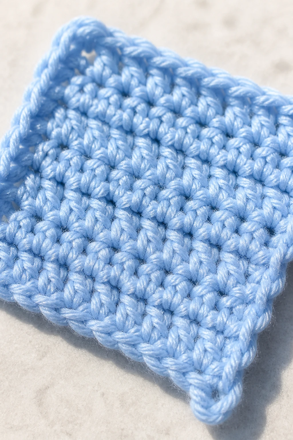 Macro image of single beginners’ crochet swatch in bright daylight
