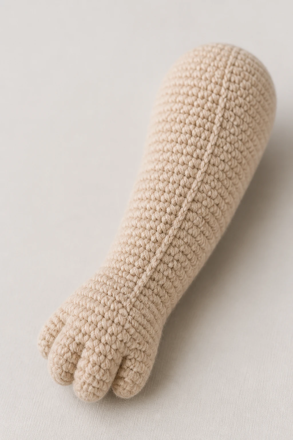 Focused image of one stuffed amigurumi limb with visible smooth seams
