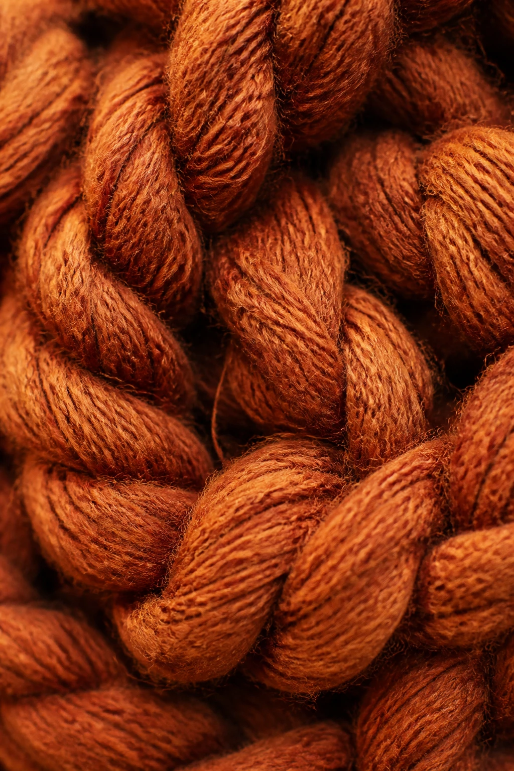Macro shot of chunky yarn fibers and twists, warm lighting, rich texture