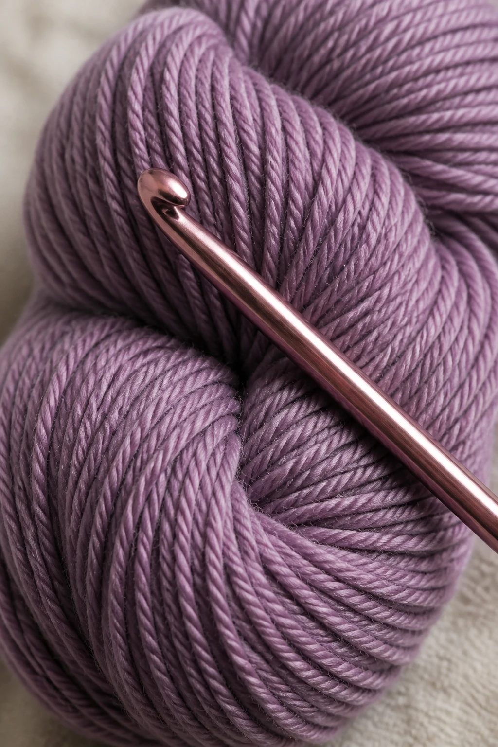 Closeup of a single skein of yarn with a crochet hook resting on it