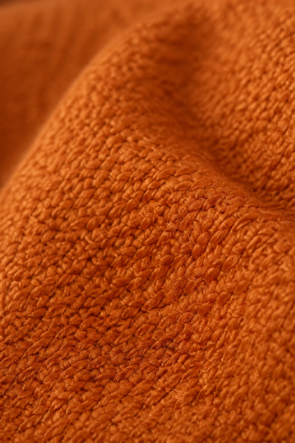 Closeup of a single warm-toned yarn color swatch on soft throw fabric